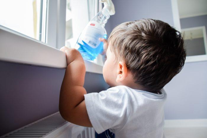 Toddler reaching up and grabbing bottle of window cleaner